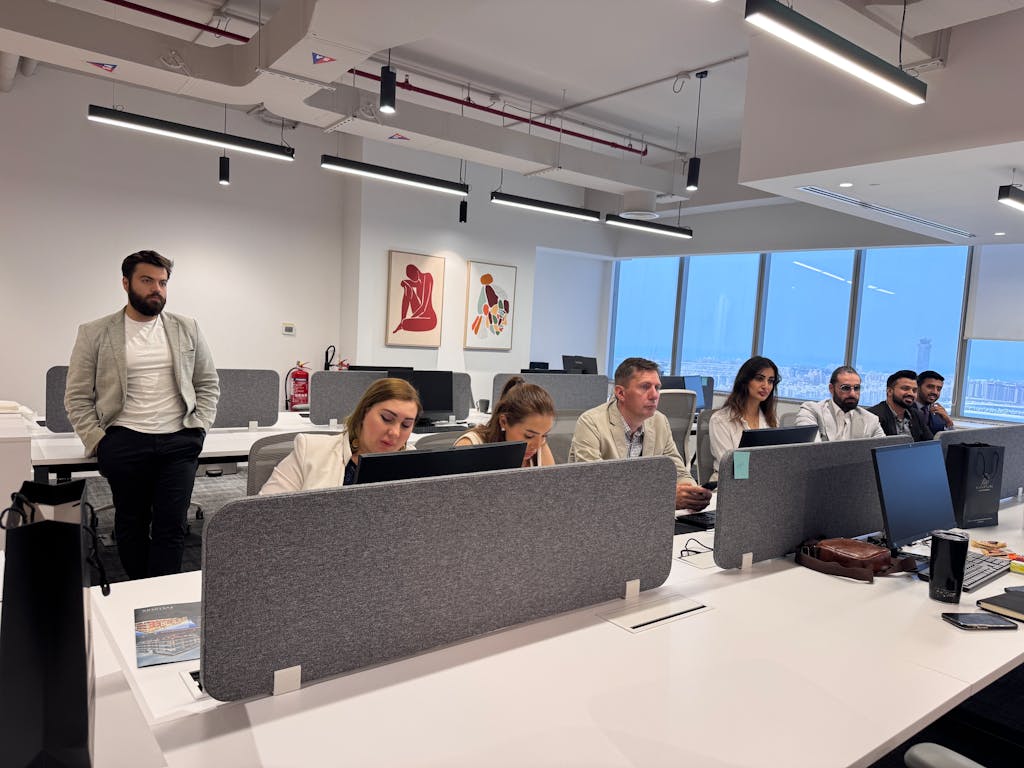 Team of professionals working in a modern office setting with computers and open workspace.